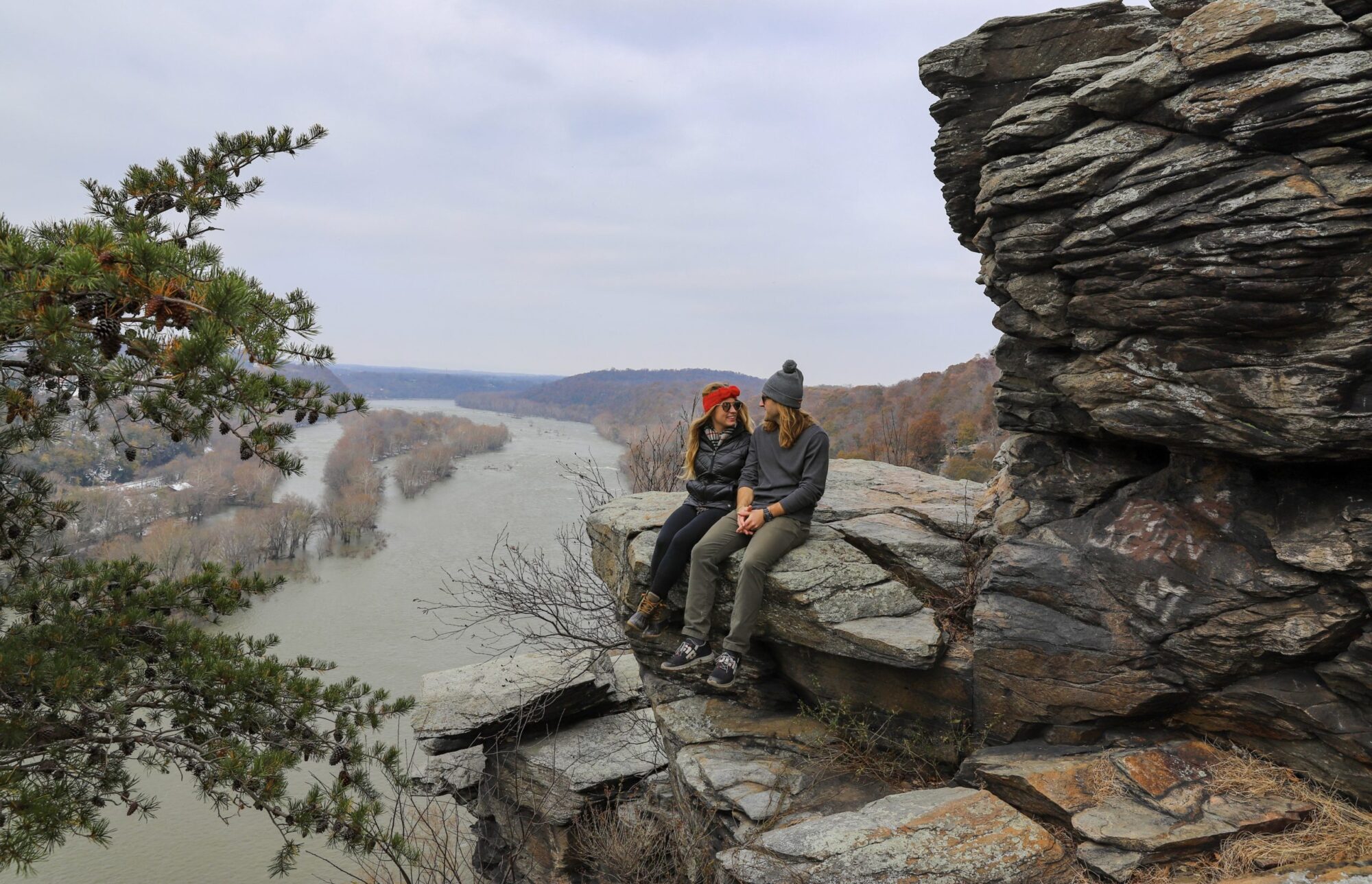 Couple sitting on a rock overlooking Harpers Ferry at the summit of Maryland Heights Overlook hiking trail